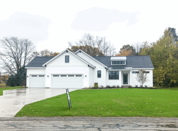 thumb-sierra Modern white house with a dark roof, large driveway, and a "For Sale" sign in the front yard. The house is surrounded by grass and trees.