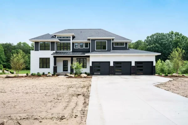 DSC04564 Modern two-story house with black and white exterior, large windows, and a three-car garage, situated in a partially landscaped yard.