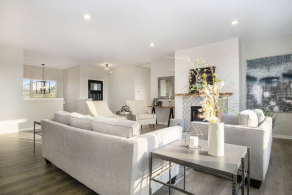 DSC07377 Modern living room featuring light gray sofas, a fireplace, minimalistic décor, a large abstract painting, and a side table with a vase of branches.