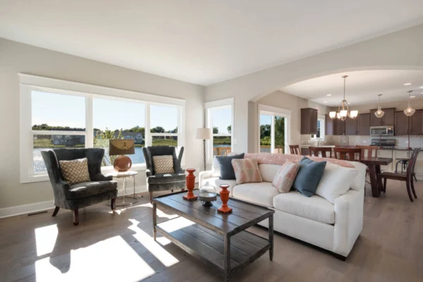 IMG_0288 Bright living room with a white sofa, two gray armchairs, and a wooden coffee table, leading to a dining area.
