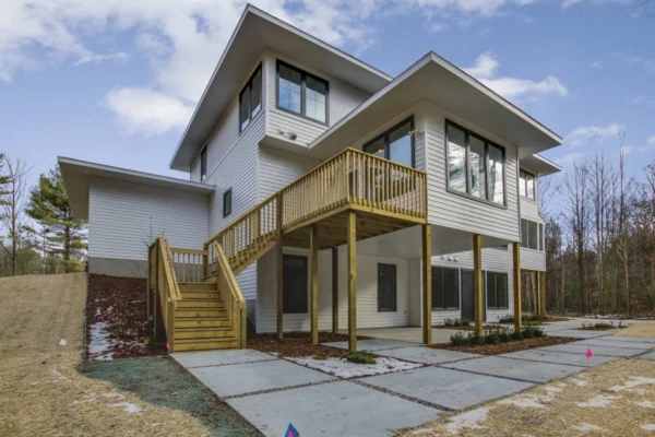 IMG_6402Blended Modern two-story house with large windows, a wooden staircase, and a partially snow-covered yard.