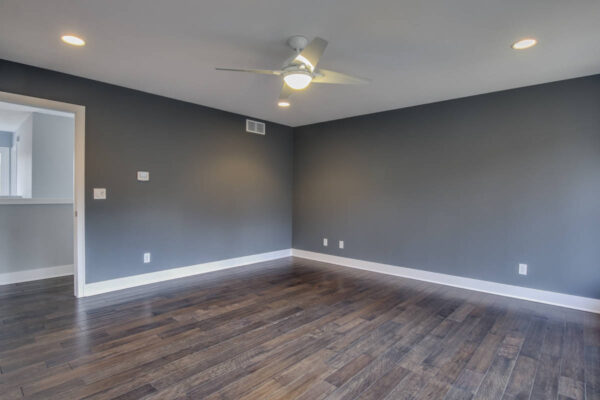 IMG_6447Blended Empty room with dark hardwood floor, gray walls, white trim, ceiling fan, and recessed lighting. Open doorway on left.
