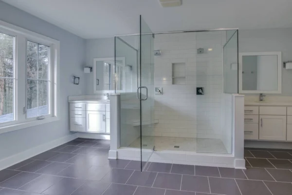 IMG_6456Blended Modern bathroom with glass shower, white cabinets, double sinks, and large windows.