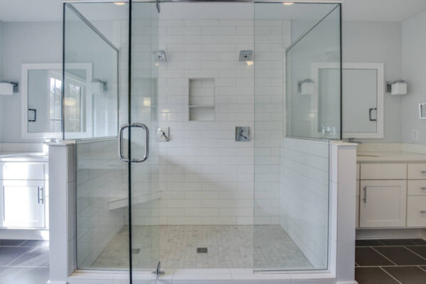 IMG_6459Blended Modern bathroom with a spacious glass shower, dual shower heads, white tiles, and a double vanity.