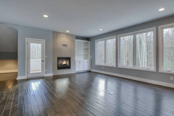 IMG_6525Blended Spacious room with wooden floors, large windows, built-in shelves, and a modern fireplace.