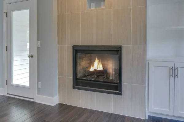 IMG_6528Blended A modern gas fireplace with a tiled surround is lit, next to a glass door and white built-in cabinet.