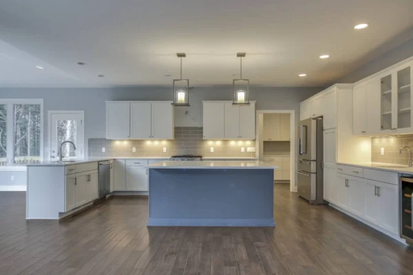 IMG_6534Blended Modern kitchen with white cabinets, gray island, pendant lights, and hardwood floors.