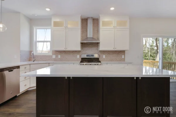 IMG_7655_blended Modern kitchen with white cabinets, stainless steel appliances, and a large dark island with marble countertops.