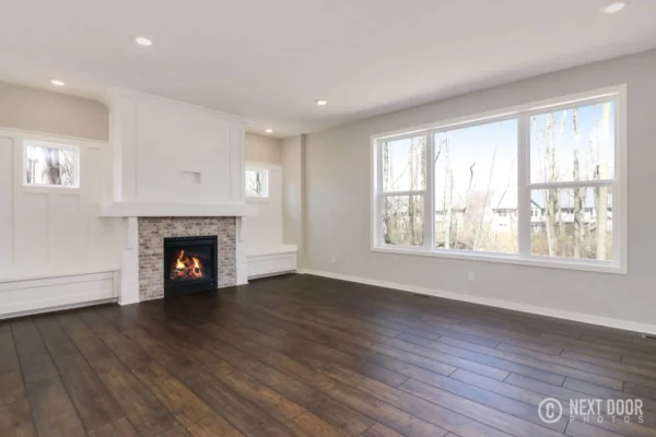 IMG_7694_blended Modern living room with dark wood floors, a white fireplace, large windows, and white walls.