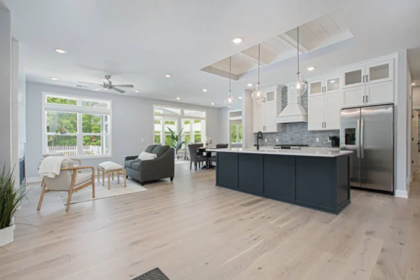 IMG_8450 Modern open-plan kitchen and living area with a central island, large windows, and light wood flooring.