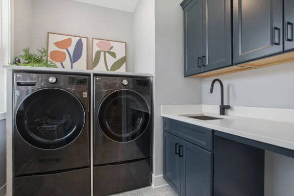 IMG_8480 Modern laundry room with black washer and dryer, dark cabinets, and wall art above.