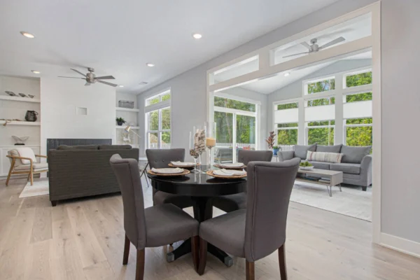 IMG_8486 Bright, modern living and dining area with gray furniture, large windows, and ceiling fans.