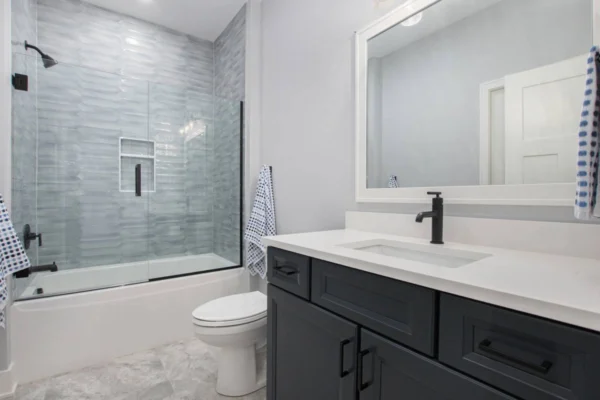 IMG_8508 Modern bathroom with a glass shower, white tub, black vanity, and checkered towels.