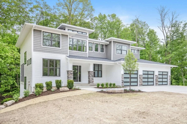 IMG_9993 Modern two-story house with large windows, surrounded by trees and a spacious driveway.