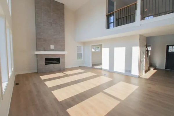 IMG_4600 Bright, modern living room with tall ceilings, large windows, light wood floors, and a tiled fireplace.