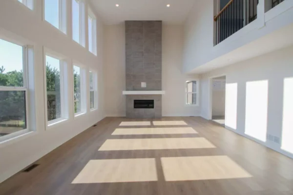 IMG_4604 Bright, spacious living room with tall windows, light wood floors, and a modern fireplace with gray tile.