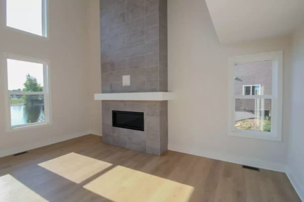 IMG_4605 Modern, bright living room with tall gray tile fireplace, wood floors, and large windows.