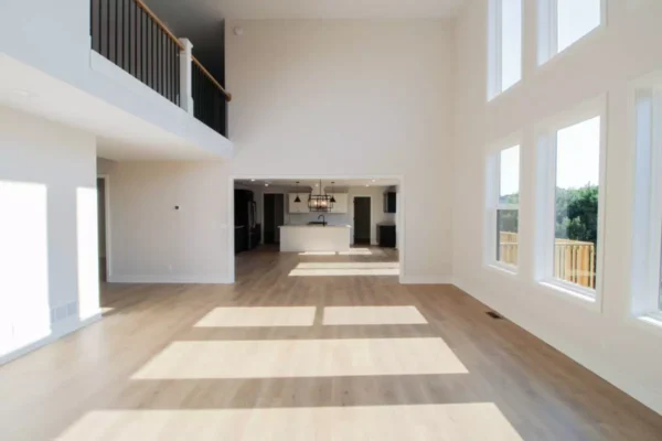 IMG_4606 Bright, modern open-concept living space with large windows, wood floors, and a view of a kitchen area.