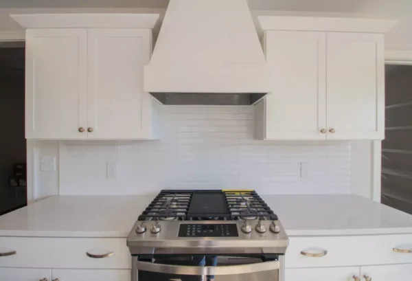 IMG_4617 Modern kitchen with white cabinets, a stainless steel stove, and a white tile backsplash.